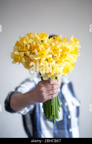 Der Mann bedeckt sein Gesicht mit einem Blumenstrauß. Stockfoto