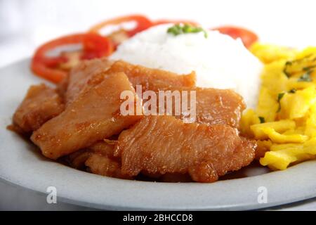 Foto frisch gekochtes philippinisches Essen namens Chicken Tocino oder geräuchertes Hühnerfleisch mit Reis, Tomaten und Rührei auf einem Teller. Stockfoto