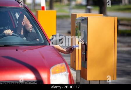 Mann Fahrer nehmen, validieren Sie ein Ticket aus dem Automaten für das Parken in privaten Bereich Stockfoto