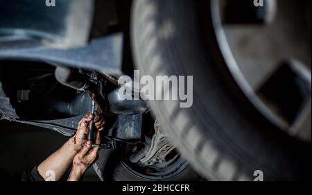 Kfz-Mechaniker tun Reparatur, Wartung Öl ändern, um das Auto auf hydraulischen PKW-Lift, Kfz-Service Stockfoto