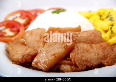 Foto frisch gekochtes philippinisches Essen namens Chicken Tocino oder geräuchertes Hühnerfleisch mit Reis, Tomaten und Rührei auf einem Teller. Stockfoto