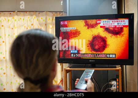 Fuji City, Shizuoka, Japan - 7. April 2020: Eine Frau schaut sich eine Nachrichtsendung im japanischen Fernsehen über die Ausbreitung des Coronavirus (COVID-19) in Japan an. Stockfoto