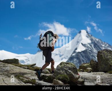 Zinal, Schweiz - 19. Juli 2019: Seitenansicht der Wandererin mit Rucksack auf felsigen Pfaden unterwegs allein in der Bergregion. Konzept des Reisens, Alpinismus und Wanderns. Stockfoto