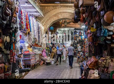 Typische Straßenansicht des Medina Bazaar von Marrakesch in Marokko. Voll mit hängenden Waren. Lieferanten und Käufer. Stockfoto