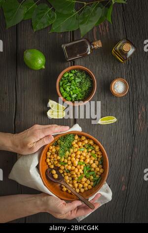 Gesunde Ernährung. Kichererbsen garnieren. Frau serviert gekochte Kichererbsen in einer Schüssel auf einem Esstisch. Vegetarisches Essen Stockfoto