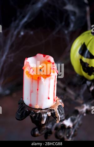 Helloween Karte mit altmodischen Vintage Kerzenhalter und brennende Kerze vor Kark Hintergrund mit bemalten gelben Kürbis. Stockfoto