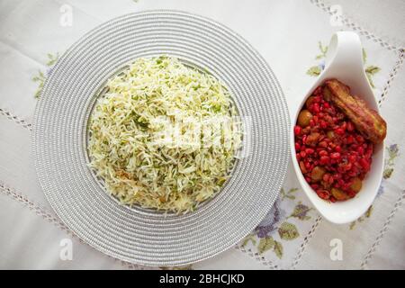 Shah Pilaf auf der weißen Tischdecke. Gehackte Dill in Pilaf in einem weißen Teller . Stockfoto