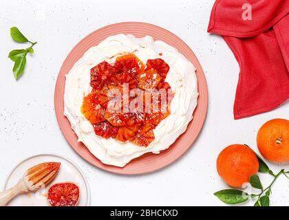 Tropischer Pavlova-Baiser-Kuchen mit Blutorange-Scheiben und Schlagsahne. Köstliches Sommerdessert. Draufsicht. Stockfoto