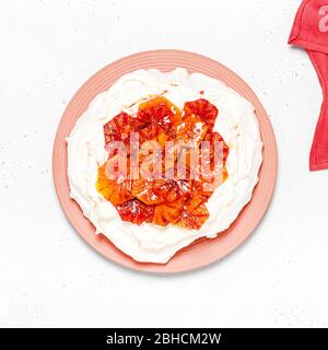 Draufsicht auf den tropischen Pavlova-Baiser-Kuchen mit Blutorange-Scheiben und Schlagsahne. Köstliches Sommerdessert. Quadratisches Bild. Stockfoto