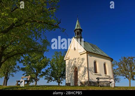 Schöne kleine Kirche mit Bäumen und blauem Himmel. Brno-Lischen - Tschechische Republik. Kapelle der Muttergottes Hilfe der Christen Stockfoto