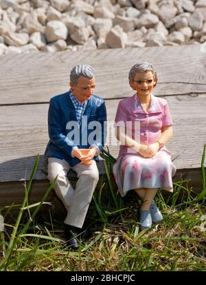 Miniaturfigur, Rentnerpaar, draußen in einem Garten sitzen, Altersvorsorge-Konzept Stockfoto