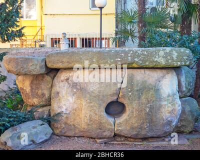 Dolmen ist ein historisches Wahrzeichen aus Steinblöcken auf dem Hintergrund moderner Häuser gebaut Stockfoto
