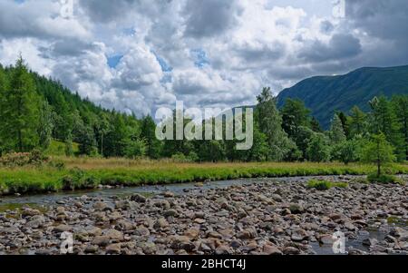 Blick über das niedrige Wasser des Flusses South Esk mit seinen Felsen und Steinen unter sich zusammenziehenden Wolken eines Sommersturms ausgesetzt. Stockfoto