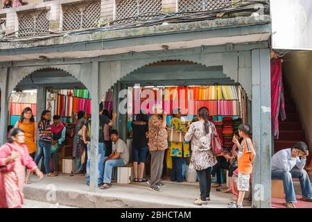 KATHMANDU, NEPAL - 29. SEPTEMBER 2012: Menschen drängen sich in einem Straßentextilien-Geschäft mit einer großen Auswahl an Stoffen aller Farben und Schattierungen Stockfoto