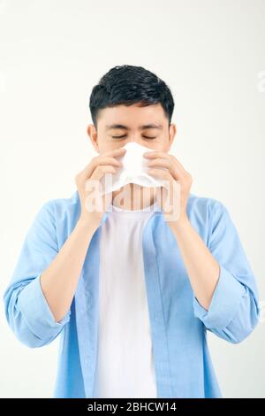 Kalter junger Mann niest in eine Serviette Stockfoto