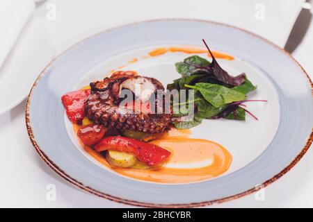 Gegrillter Oktopus mit Gemüse und Tintenfischsauce. Restaurant, Lifestyle, Reiseessen - gegrillter Oktopus mit Gemüse Restaurantmenü. Italienisch Fr. Stockfoto