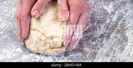 Schöne Frauenhände Kneten Teig auf dem Holztisch, so dass Teig von weiblichen Händen Stockfoto