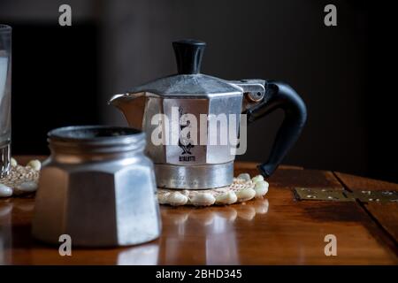 Ein traditioneller Bialetti Moka Topf sitzt im Morgenlicht auf einem Holztisch. Stockfoto