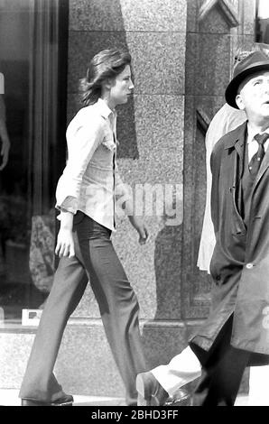 Das tägliche Leben auf den Straßen in Manchester, England, Großbritannien im Jahr 1974. Ein junger Teenager mit langen Haaren geht auf dem Bürgersteig an anderen Fußgängern vorbei. Stockfoto