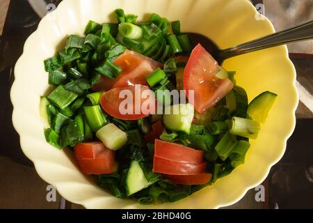 Der frische Salat mit Gurke und Tomate im Teller auf dem Tisch.Frische Produkte aus der Fütterung Nahaufnahme Stockfoto