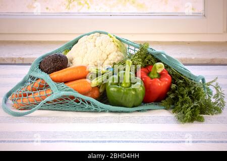 Frisches Gemüse in einem blauen Netzbeutel, wiederverwendbar, nachhaltig, umweltfreundlich, Erdtag, kein Plastikkonzept. Verschiedene Gemüse: Paprika, Karotten, Blumenkohl Stockfoto