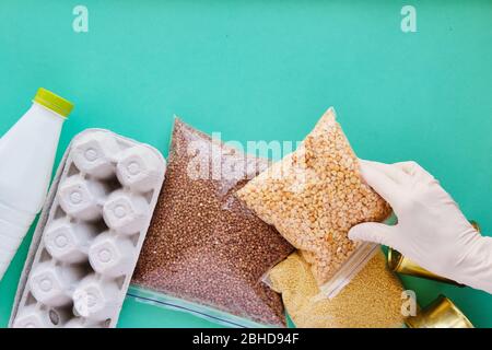 Verschiedene Produkte und eine Hand in einem medizinischen Handschuh. Quarantäne-Food-Delivery-Konzept Stockfoto