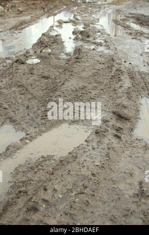 Schmutzige Feldweg mit Spur, Radspuren, brauner Lehm und Pfützen in Russland. Stockfoto