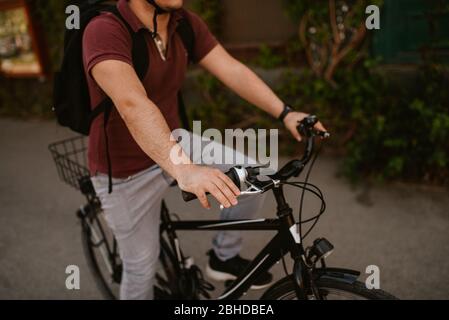Nahaufnahme des jungen kaukasischen Radfahrers mit Helm und Sonnenbrille Auf einem Fahrrad vor dem Fenster Stockfoto