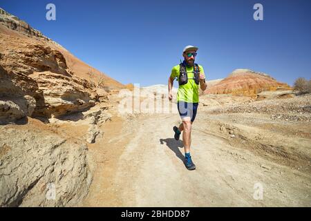 Runner Athlet mit Bart, der auf der freien Wildbahn Trail in Ton Berge in der Wüste Stockfoto