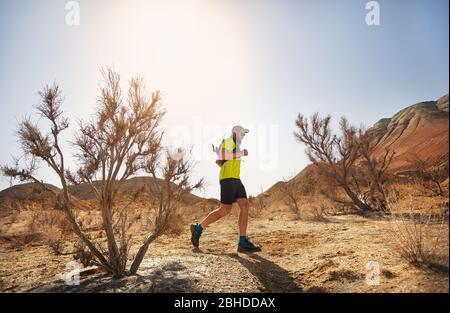 Runner Athlet mit Bart, der auf der freien Wildbahn Trail am roten Berge in der Wüste Stockfoto