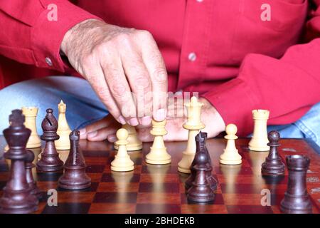 Mann in einem roten Hemd spielt Schach Stockfoto