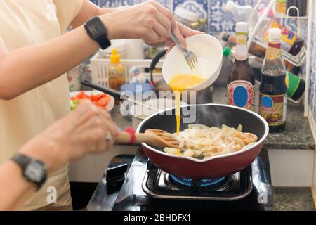 Frau, die während der Covid-19 Quarantäne Essen kocht und Ei in die Pfanne gießt. Stockfoto
