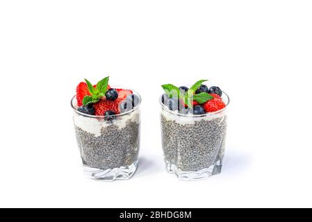 Zwei Gläser Chia Pudding mit Kokoscreme, Erdbeere, Heidelbeere und Minze auf Weiß isoliert. Stockfoto