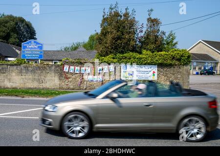 Chippenham, Wiltshire, Großbritannien, 25. April 2020. Ein Auto ist abgebildet, als es an einem Schild mit dem Titel „Danke NHS“ vorbeifährt, das an einer Schulwand gegenüber dem Chippenham Community Hospital angebracht wurde. Kredit: Lynchpics/Alamy Live News Stockfoto