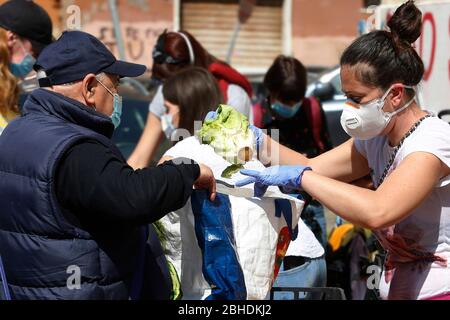 Roma, Italien. April 2020. Rom, 25. April 2020. Coronavirus-Sperrung. In ganz Italien hat die Sperrung des Coronavirus die Wirtschaftskrise verbessert, so dass in vielen Nachbarschaften Vereine und Freiwillige Essen an weniger wohlhabende Menschen verteilen. Am 25. April (Jahrestag der Befreiung Italiens vom nazi-Faschismus und Jahrestag des Widerstands) verteilen Freiwillige des Roten Labors zusammen mit Lebensmitteln, einer roten Nelke und einem Foto. Foto Samantha Zucchi Insidefoto Quelle: Insidefoto srl/Alamy Live News Stockfoto