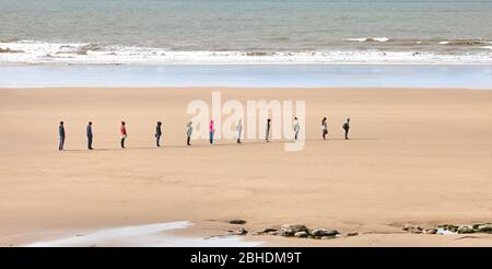 Soziale Distanz in einer geordneten Schlange am Dunraven Beach an der Glamorgan Heritage Coast in South Wales, Großbritannien Stockfoto
