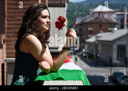 Turin, Italien. April 2020. TURIN, ITALIEN - 25. April 2020: Eine Frau hält eine rote Blume auf ihrem Balkon als Teil des Flash Mob, um den Tag der Befreiung zu feiern. Am 25. April ist der Tag der Befreiung (Festa della Liberazione), der die Befreiung Italiens von den nazis und Faschisten und das Ende des Zweiten Weltkriegs für Italien markiert. Die wiederkehrende Fackelprozession und Demonstration werden aufgrund der COVID19-Beschränkungen nicht gefeiert. (Foto: Nicolò Campo/Sipa USA) Quelle: SIPA USA/Alamy Live News Stockfoto