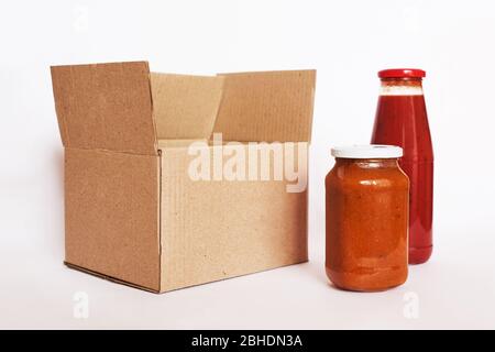 Spendenbox mit hausgemachter Konserve auf weißem Hintergrund. Karton mit Spende Lebensmittel. Konzept für die Lieferung von Lebensmitteln Stockfoto