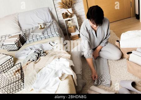 Schöne junge Brünette Frau Falten Dinge Stockfoto