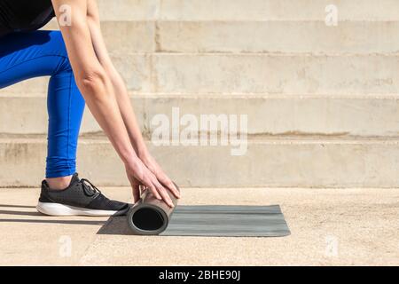 Nahaufnahme Frau Hände Rollen eine Gummi-Yoga-Matte Stockfoto