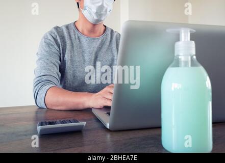 Eine Person, die während einer Epidemie zu Hause auf einem Laptop arbeitet Stockfoto