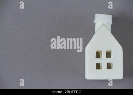 Stay Home Konzept, Spielzeug weiße Hausfigur auf grauem Hintergrund, Quarantäne Hintergrund Stockfoto