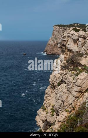 Wilde Oberfläche der Klippen an der Westküste der Insel im pak Parco Naturale Regionale di Porto Conte. Leichte Wellen des Mittelmeers. Blauer Himmel. Stockfoto