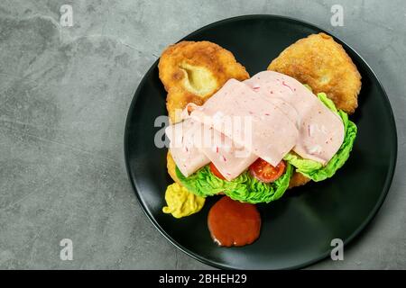 Traditionelles navajo Fladenbrot, Taco mit Salat, Tomaten, Schinken und Sauce auf dem schwarzen Teller, Draufsicht. Indisches navajo Fladenbrot, Fastfood. Stockfoto