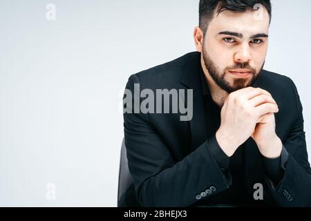 Junge schöne Mann mit Bart und Hand auf Kinn Denken über Frage, nachdenkliche Ausdruck. Nachdenkliche Gesicht. Zweifelskonzept. Stockfoto