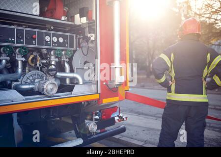 Feuerwehrmann in Aktion in der Nähe eines Feuerwehrwagens. Angriff, Gefahr, Feuer. Stockfoto