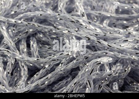 Makro-Schuss von glitzernden Metallic-Stickgarnen in Silber und blassblauen Farben zufällig in einem Haufen angeordnet. Stockfoto