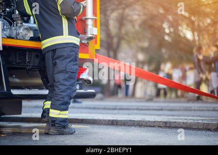 Feuerwehrmann in Schutzuniform. Feuerwehrmann in der Nähe eines Feuerwehrwagens. Feuerwehrwagen mit Löschausrüstung. Stockfoto