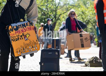 25. April 2020, Hessen, Frankfurt/Main: Demonstranten stehen auf dem Gelände eines Luxushotels in einer Reihe, jeweils zwei Meter voneinander entfernt, mit Koffern und Umzugskartons vor der Alten Oper. Auf dem Koffer links steht "Leben für Menschen statt Profit". Zum Thema "Flüchtlinge und Wohnungsmangel in der Corona-Krise" fanden vor zwei Hotels und einer Jugendherberge Aktionen statt. Foto: Frank Rumpenhorst/dpa Stockfoto