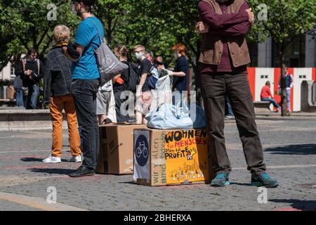 25. April 2020, Hessen, Frankfurt/Main: Demonstranten stehen auf dem Gelände eines Luxushotels in einer Reihe, jeweils zwei Meter voneinander entfernt, mit Koffern und Umzugskartons vor der Alten Oper. Auf einer der Boxen steht: "Leben für Menschen statt Gewinn". Zum Thema "Flüchtlinge und Wohnungsmangel in der Corona-Krise" fanden vor zwei Hotels und einer Jugendherberge Aktionen statt. Foto: Frank Rumpenhorst/dpa Stockfoto